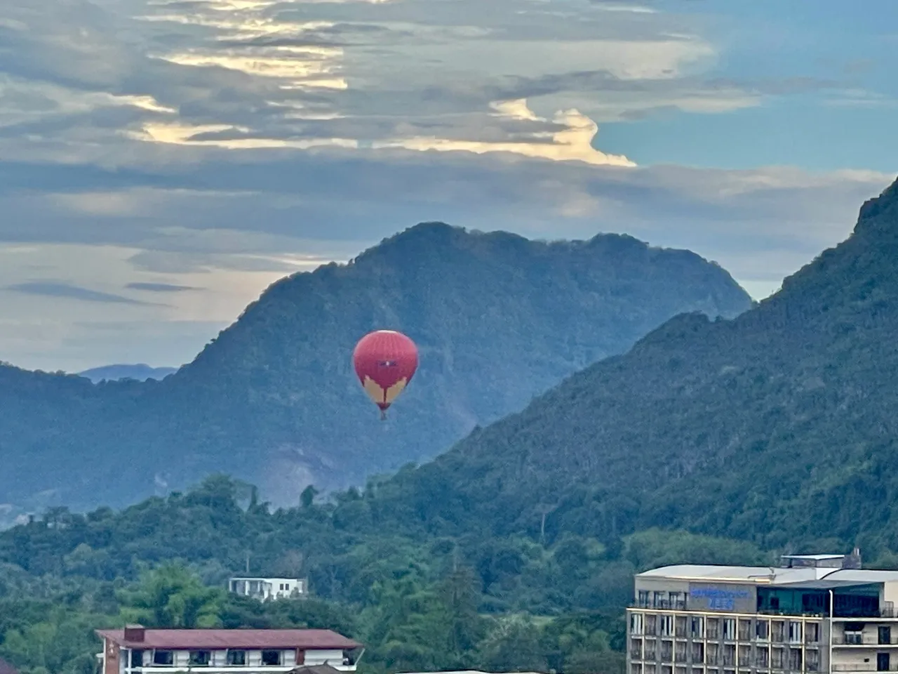 A hot air balloon drifting over the Vang Vieng karst mountains at dusk