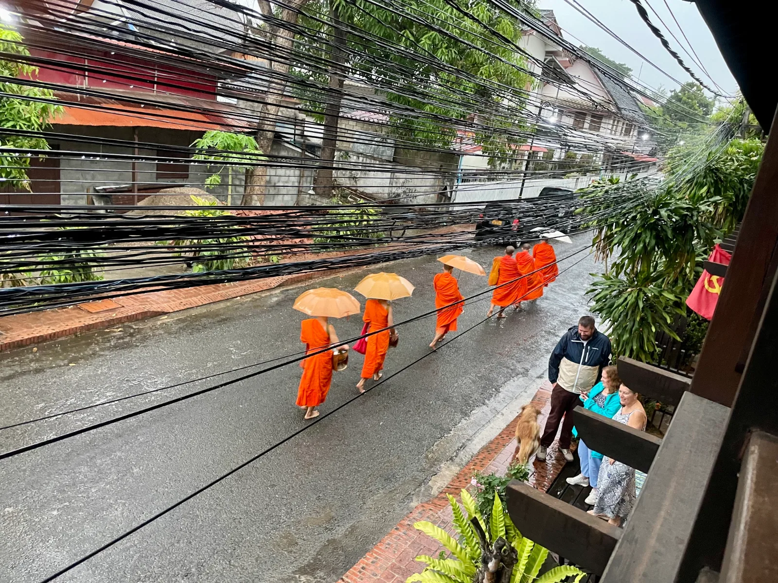 A group of monks with umbrellas walking under power lines in Laos