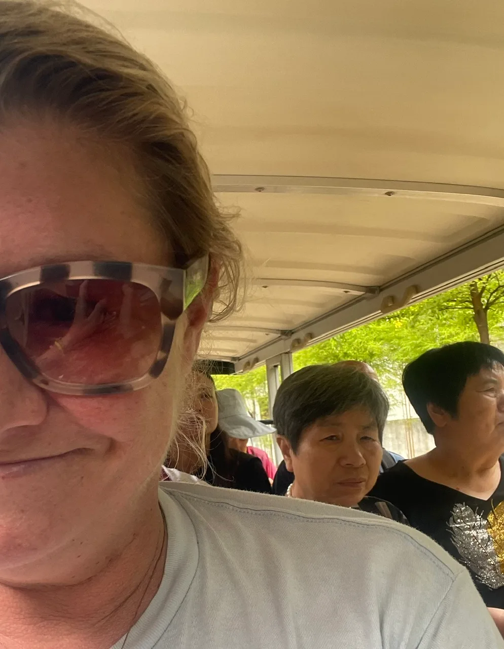 A sweaty Western woman on a tram with Chinese tourists in Laos