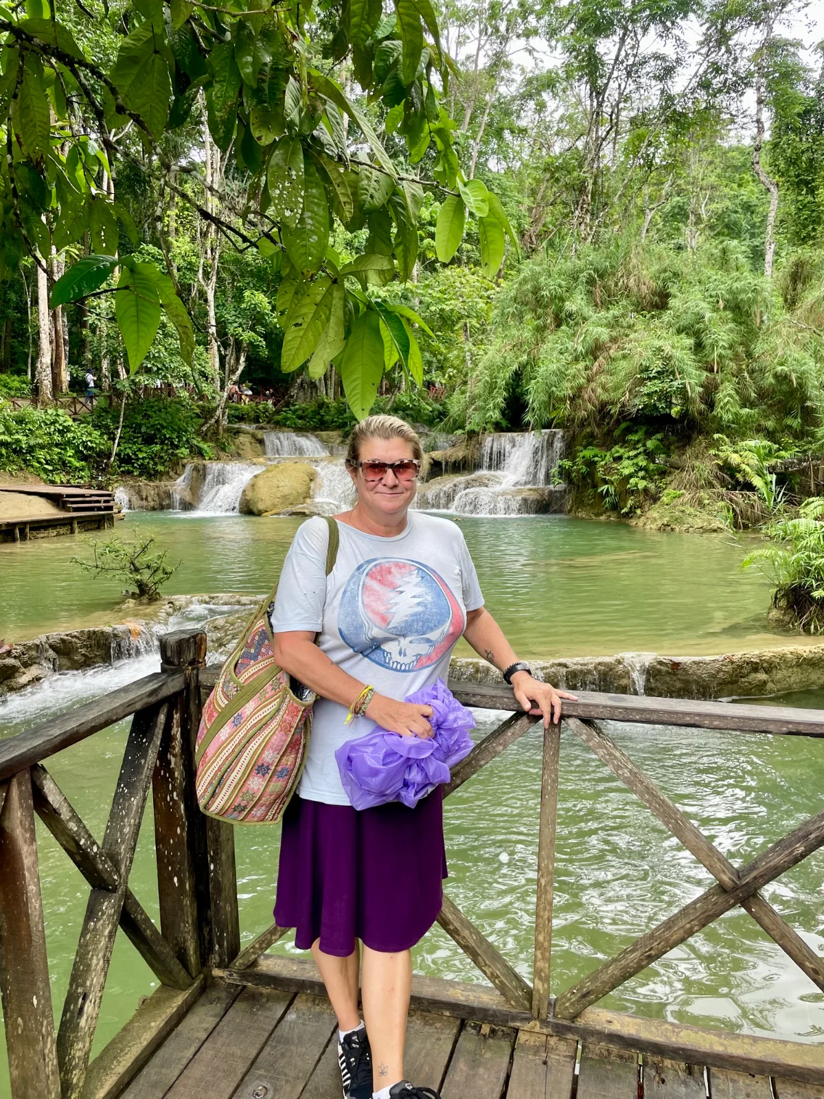 A woman standing in front of the Kuang Si Waterfalls in Laos