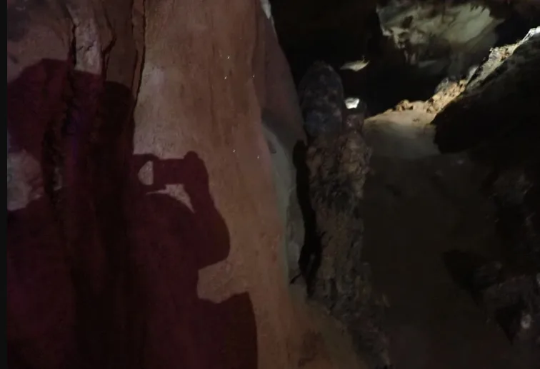 A shadow if a woman taking a photo in a cave in Laos